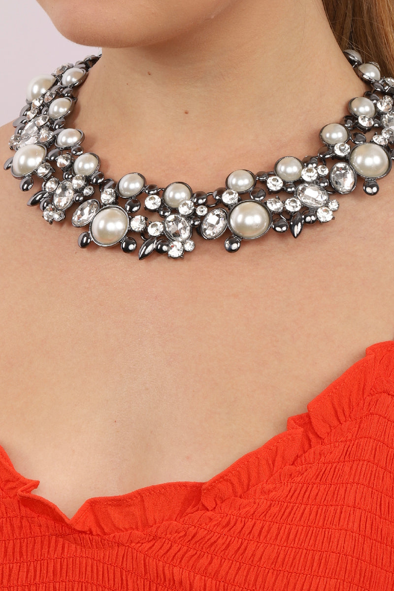 Upclose view on Clementine white statement necklace on model. Necklace features beaded crystals and pearl.