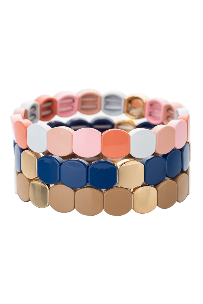 3 piece bracelet set all with rounded square enamel beads. First bracelet features pink and white beads. Second bracelet features navy blue and gold beads. Third bracelet features gold toned beads. All bracelets are stretchy.